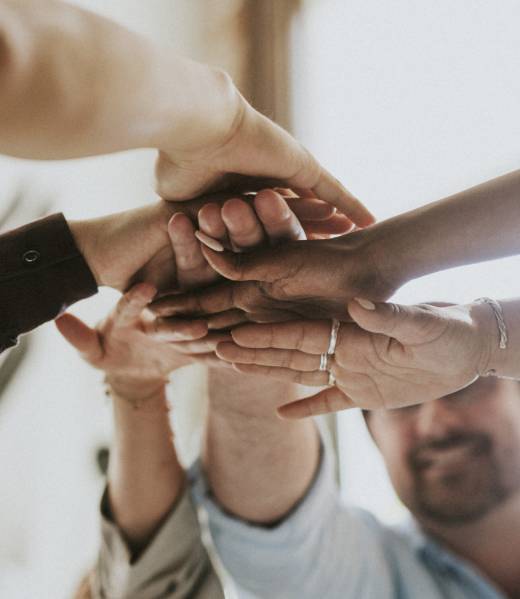 Happy team putting their hands together for success